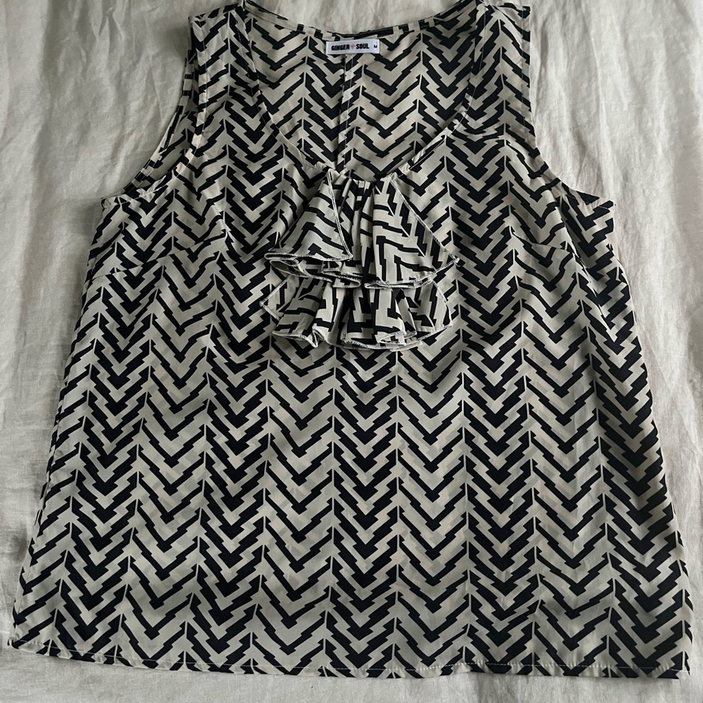 A sleeveless black and beige top with front detailing.